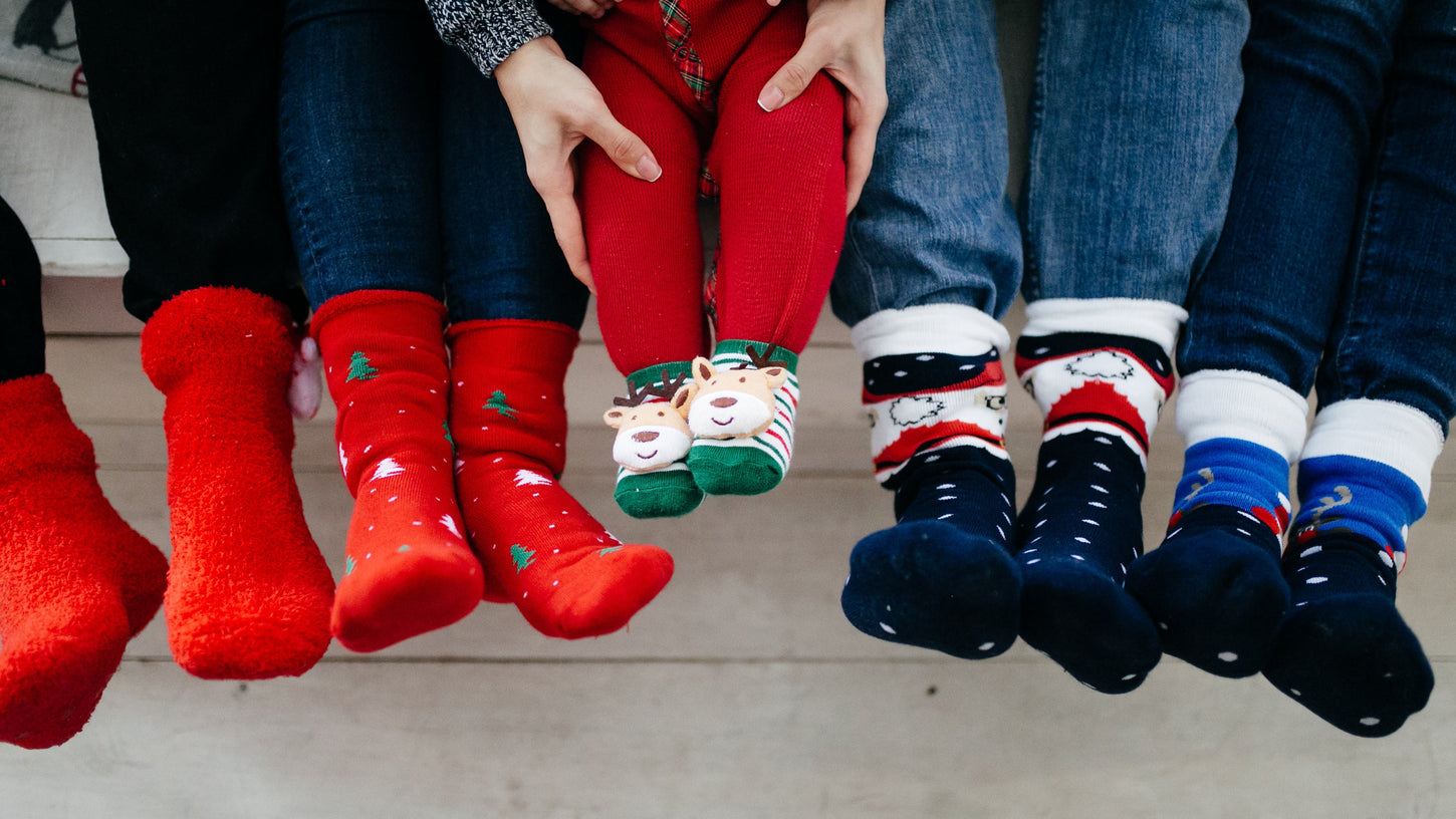 Children's feet wearing colorful Christmas-themed socks and boots.