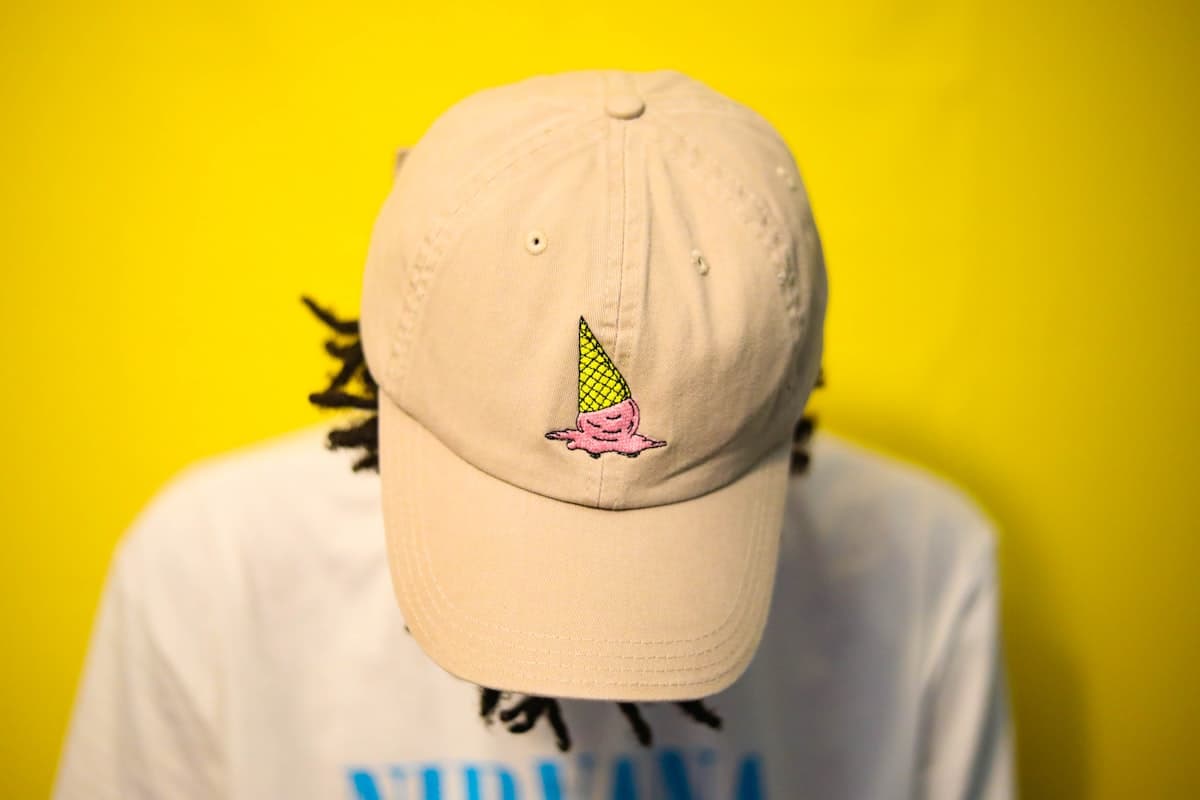 Cream dad cap worn against a yellow wall